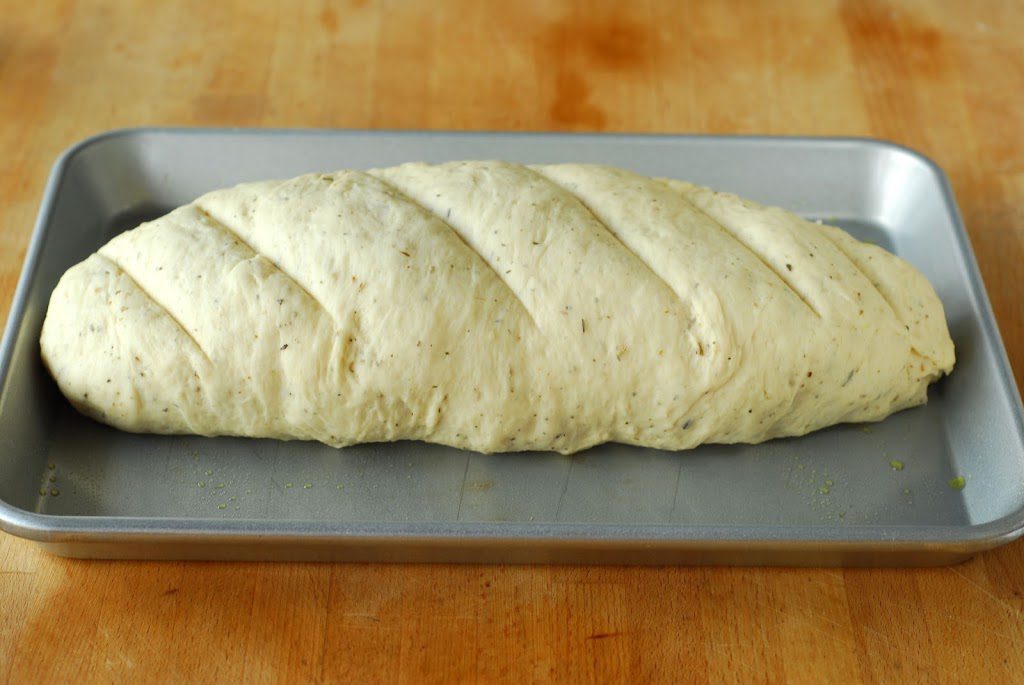 Bread dough shaped into loaf and scored on cookie sheet