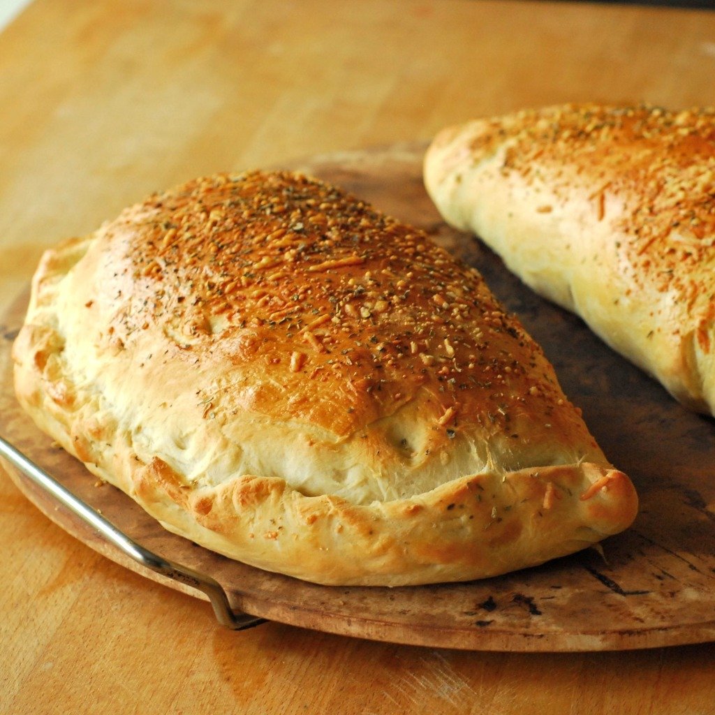 Cooked whole calzones on pizza stone