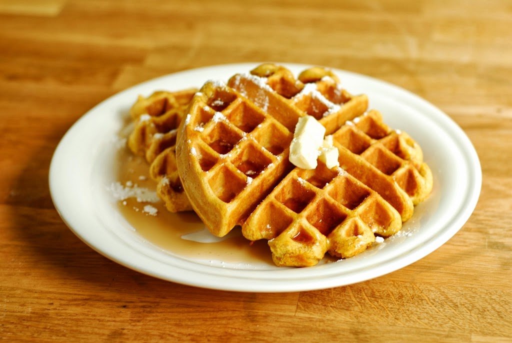 pumpkin waffles with butter and syrup on a white plate