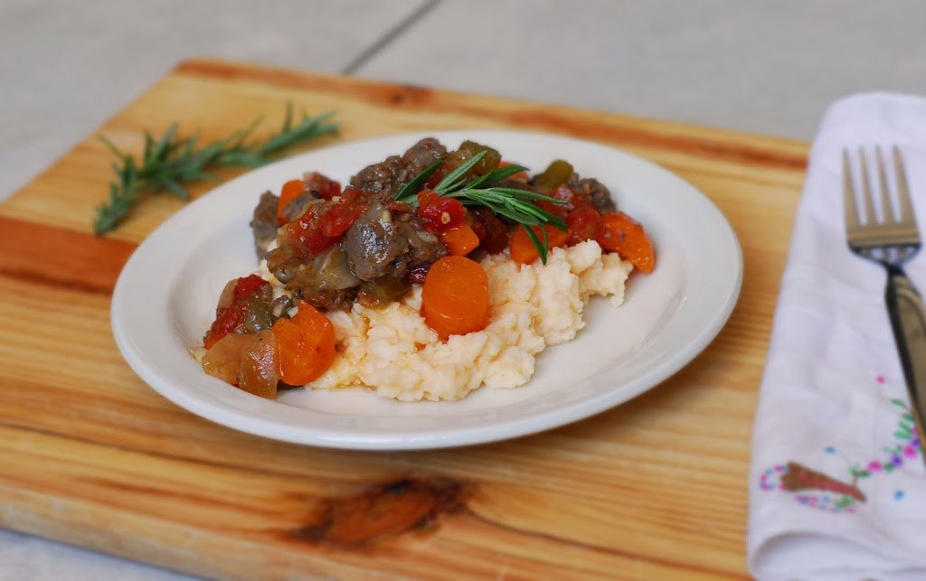 Beer Braised Stewed Beef from A Duck's Oven. Beef braised in beer and stewed with tomatoes, carrots, onions, and sausage, served over cheesy grits or pap.