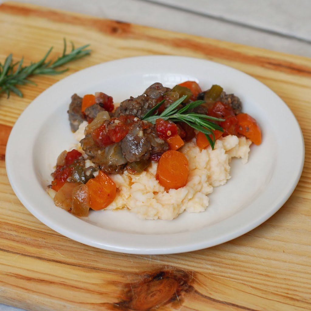 Beer Braised Stewed Beef from A Duck's Oven. Beef braised in beer and stewed with tomatoes, carrots, onions, and sausage, served over cheesy grits or pap.