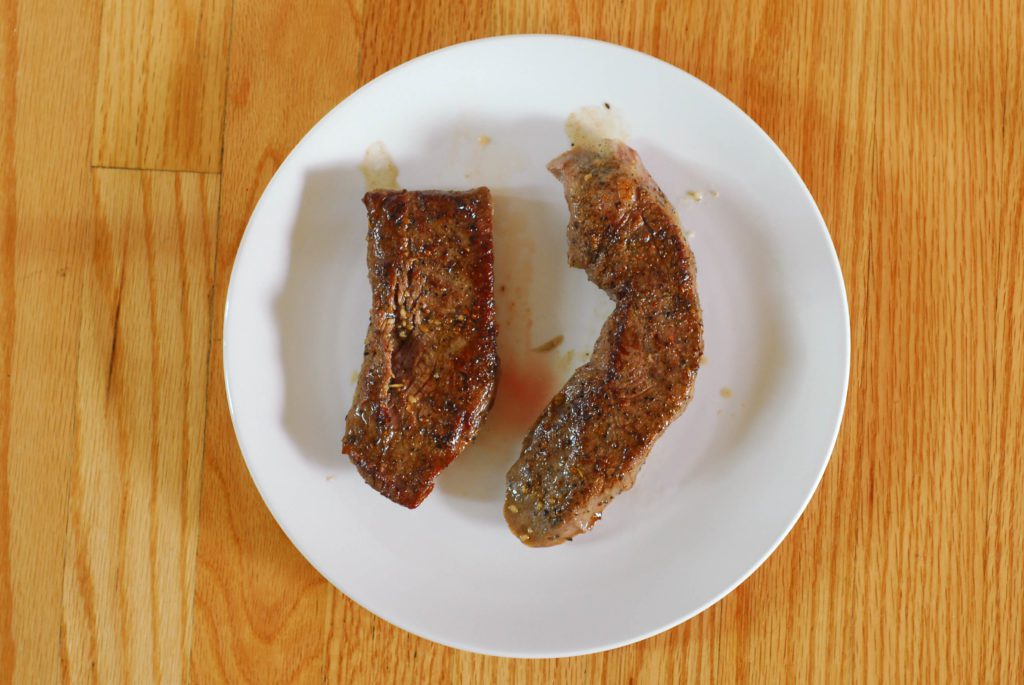  Steak poêlé sur une assiette blanche à la surface du bois