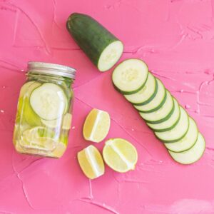 sous vide cucumber lime tequila next to sliced limes and cucumbers