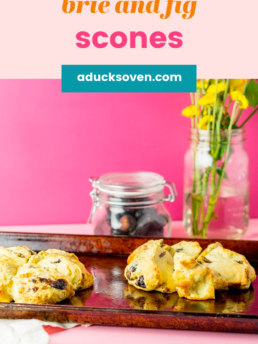 Two Brie and Fig Scones on a platter with yellow flowers in a glass vase in the background.