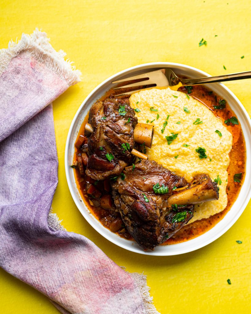 Beer braised pork shanks and polenta in a white serving plate