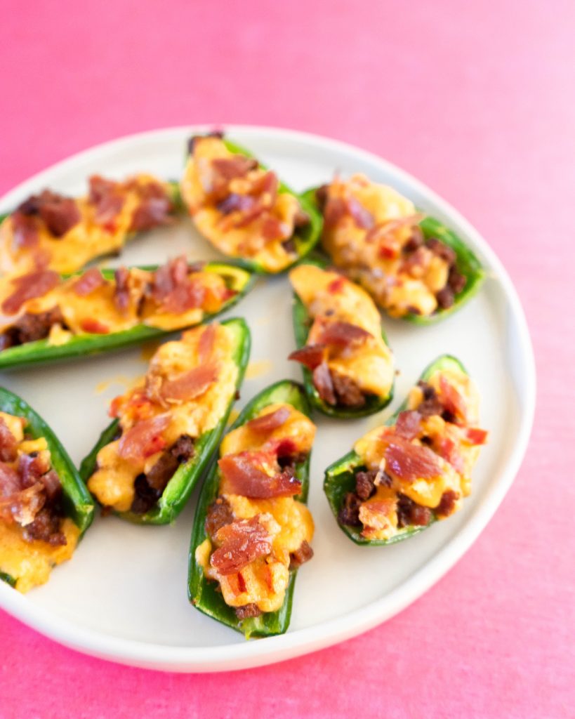 Jalapeno poppers on white platter on pink background