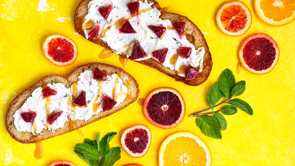 Blood Orange and Mint Ricotta Toast on yellow backdrop
