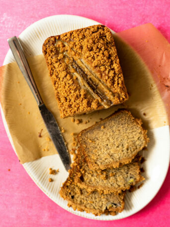 Banana bread on a white platter on a hot pink surface