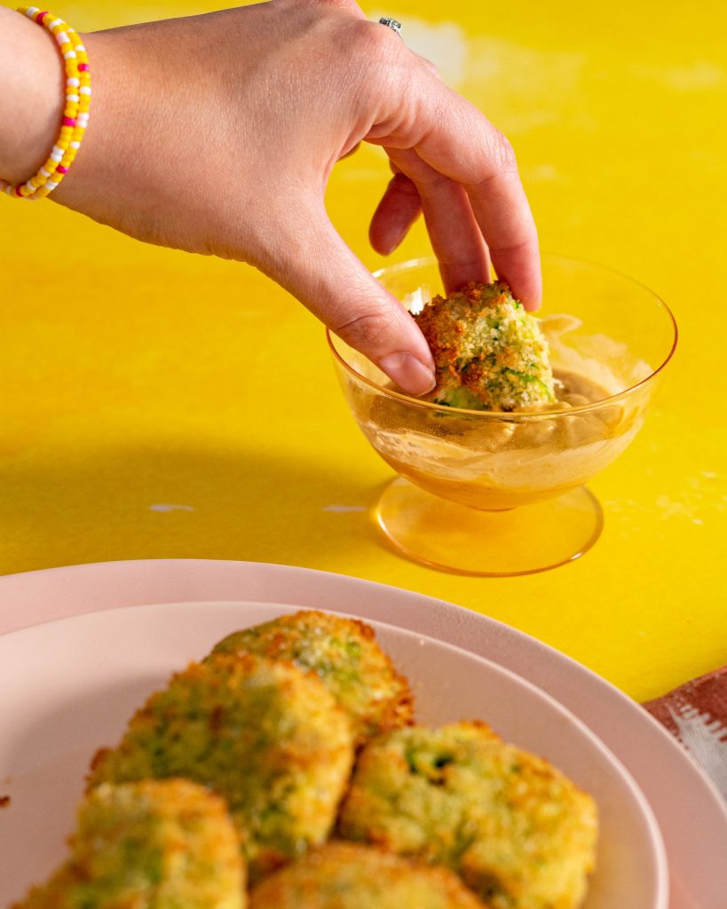 Hand dipping air fryer zucchini fritter into sauce