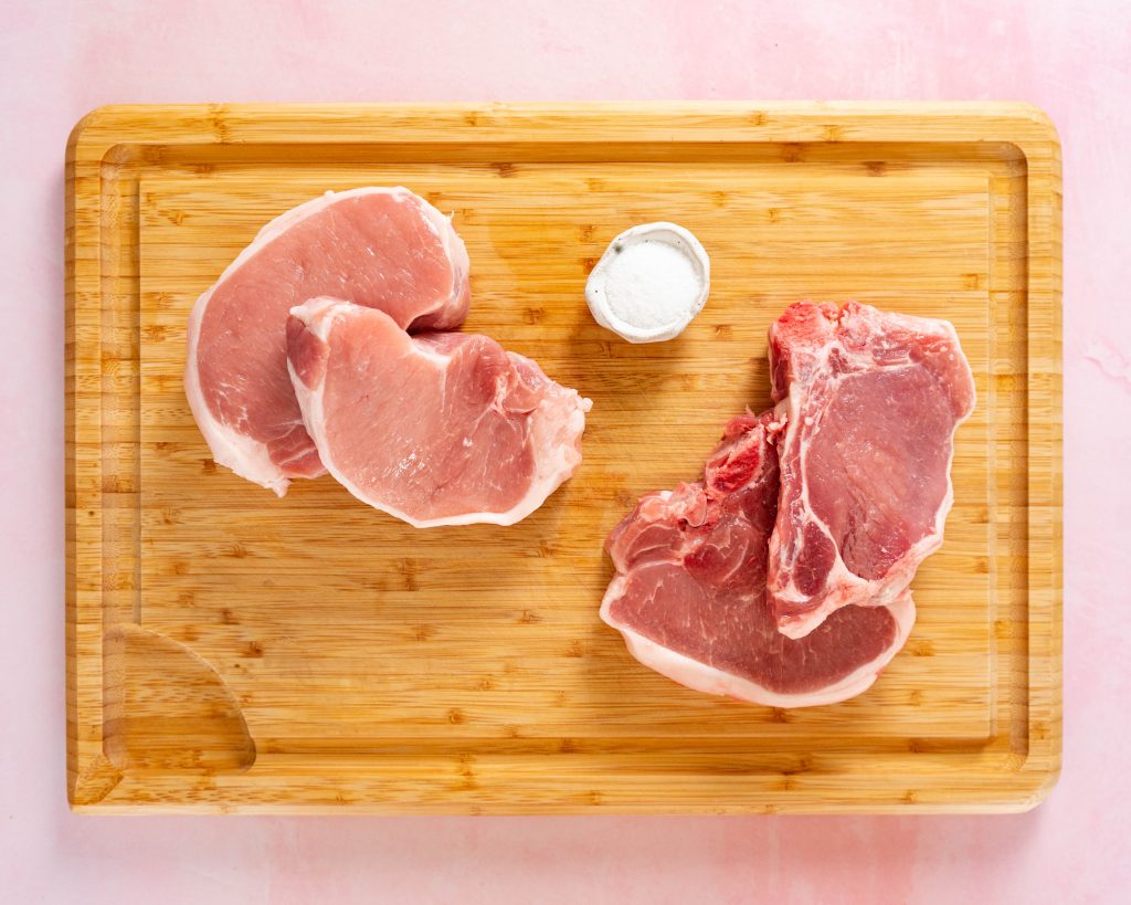 Boneless and bone-in pork chops on wood cutting board