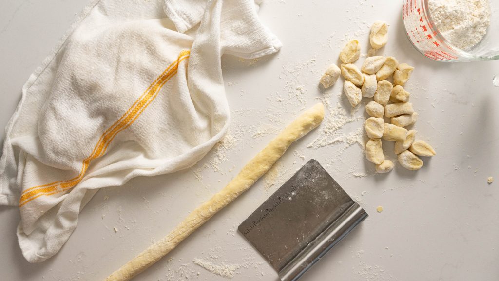 Rolling out gnocchi on floured white surface