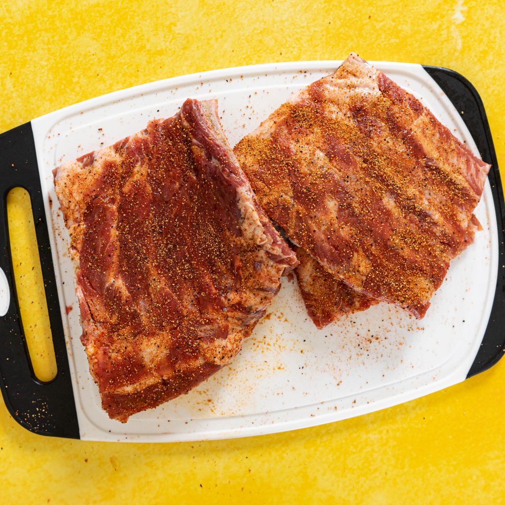seasoned ribs on cutting board on yellow surface