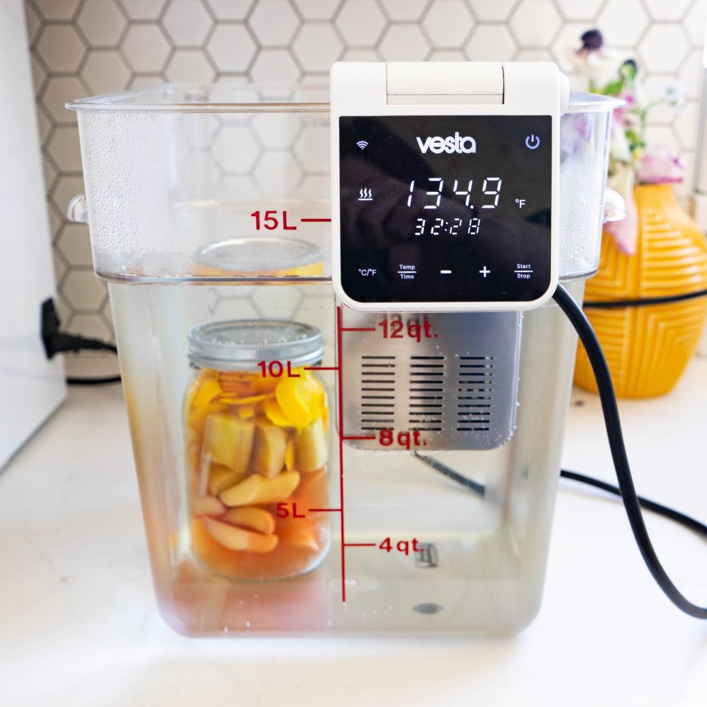 Jar of fruit and vodka cooking in sous vide water bath