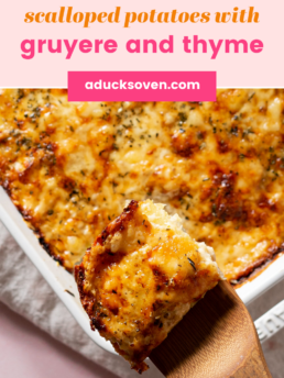 Scalloped potatoes with gruyere and thyme in a white casserole dish with one slice lifted up on a spatula.