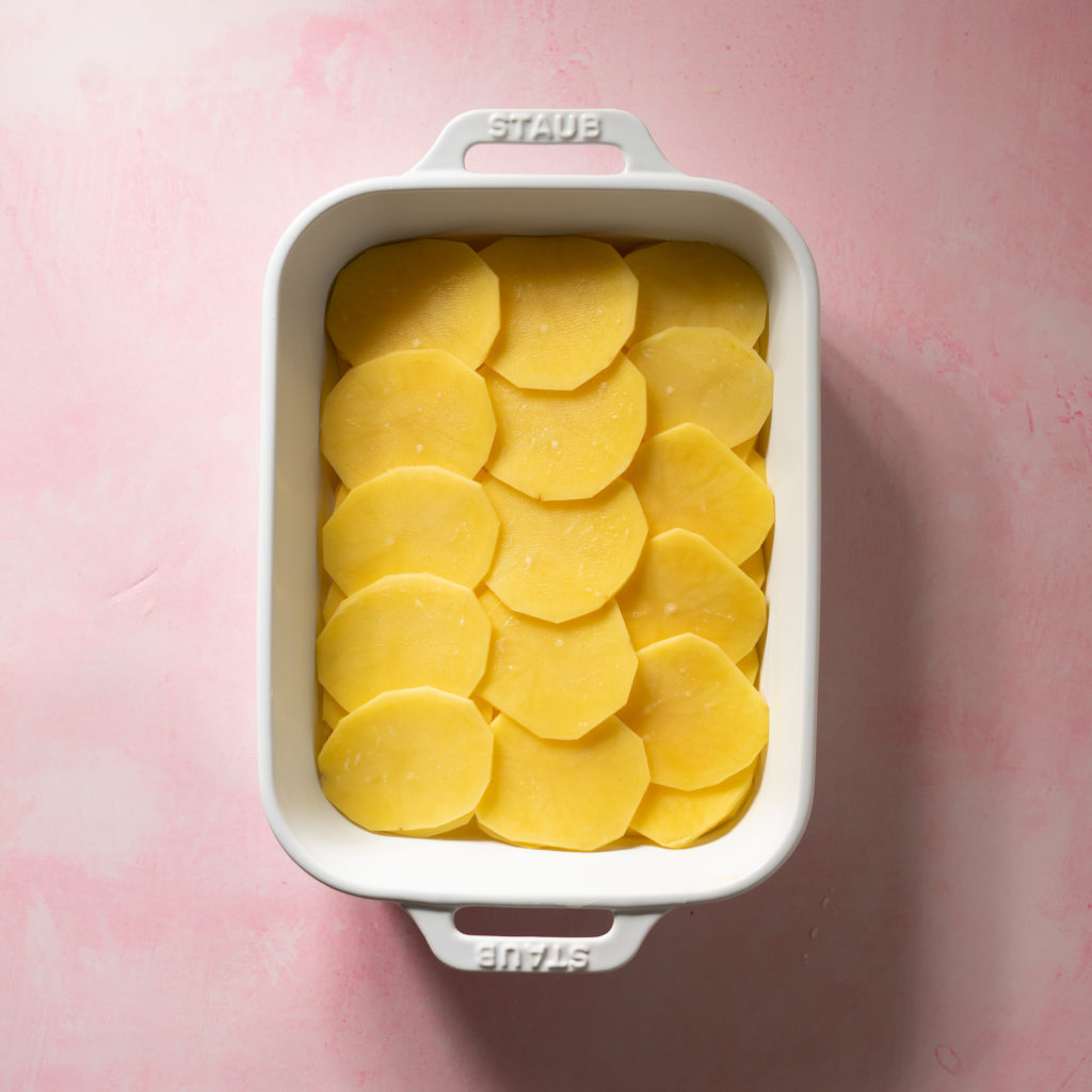 Scalloped potatoes in greased baking dish