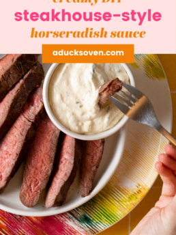 Medium rare sliced steak on a white plate with a small white bowl of DIY horseradish sauce by it.
