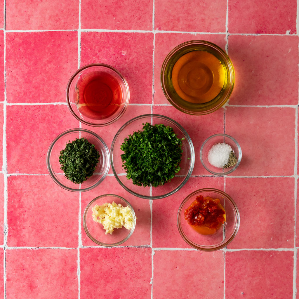 Chimichurri ingredients on pink tile background