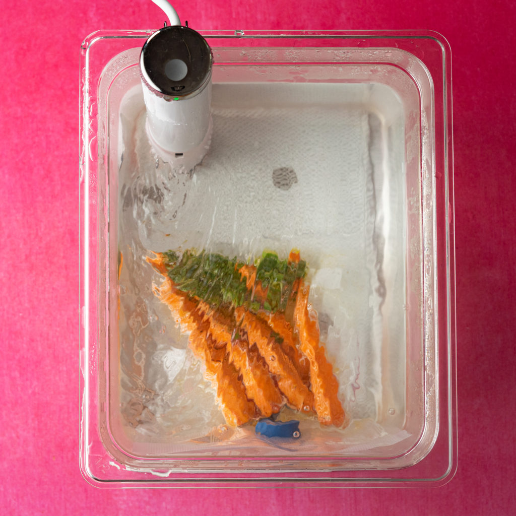 Vacuum sealed carrots in sous vide water bath.