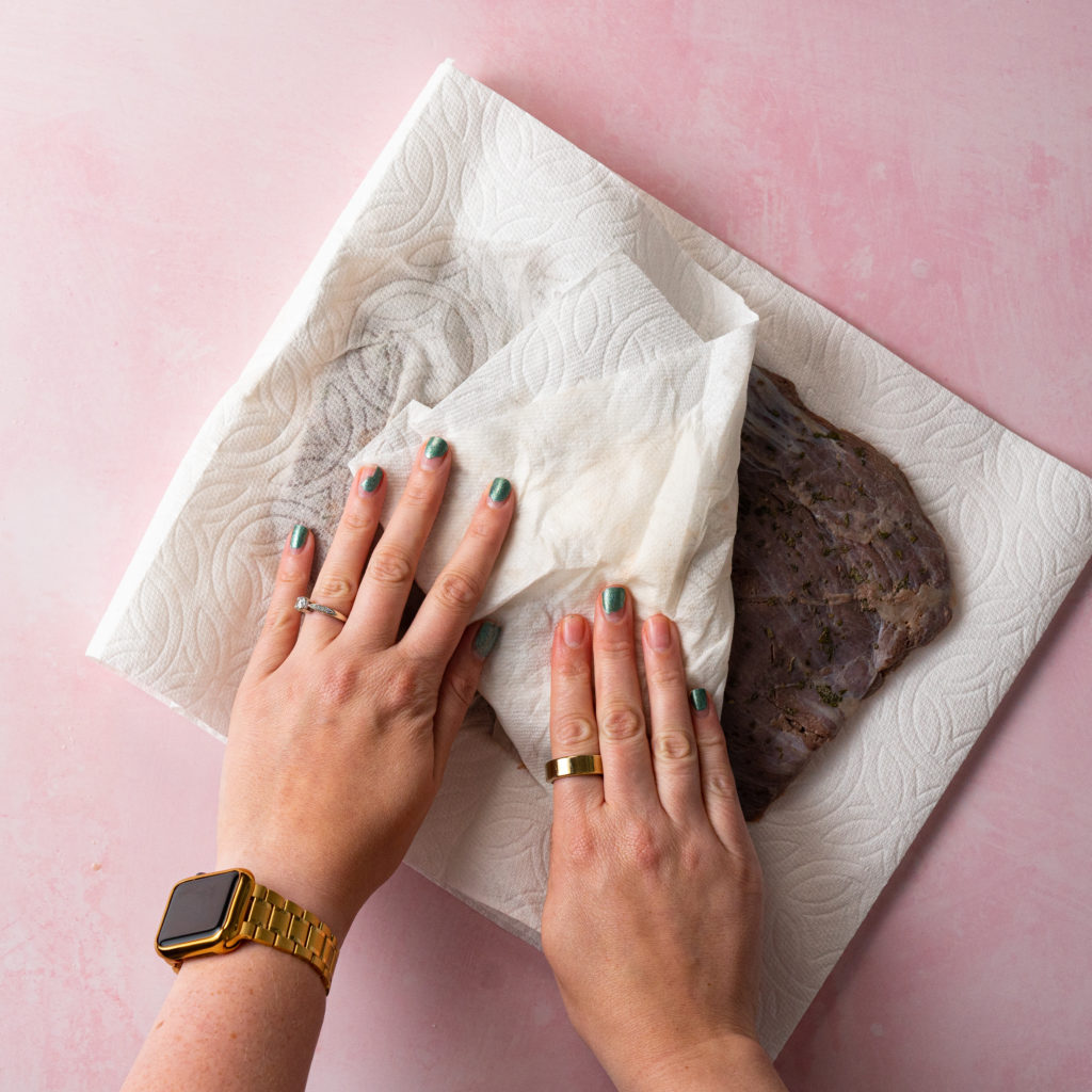 Sous vided flank steak being dried with paper towels.