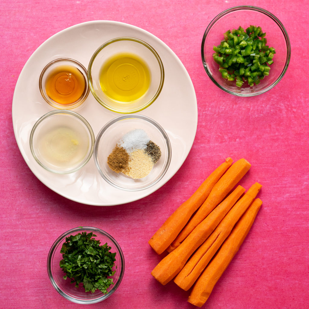 Ingredients for the sous vide carrots on a pink surface.