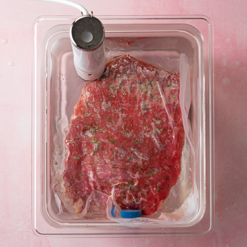 Vacuum sealed flank steak cooking in sous vide water bath.