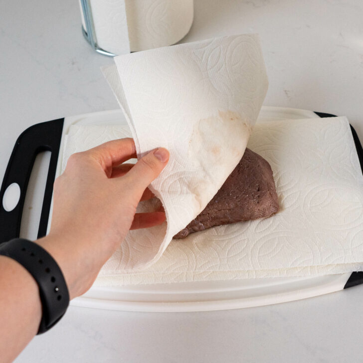 Patting steak dry with paper towels