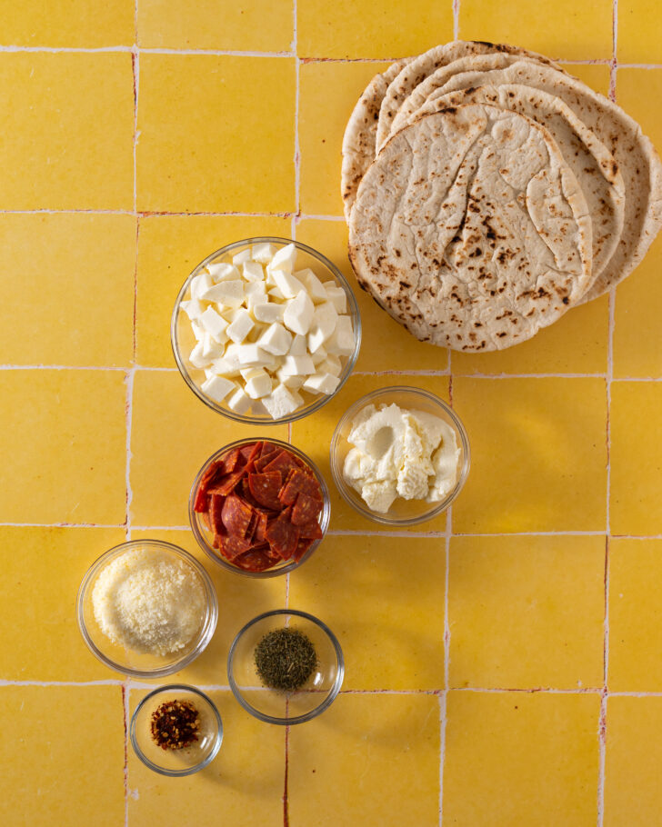 Pita calzone ingredients on yellow surface.