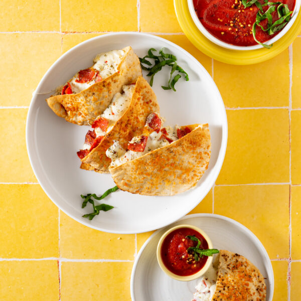 Pita calzones on a white plate with bowl of dipping sauce