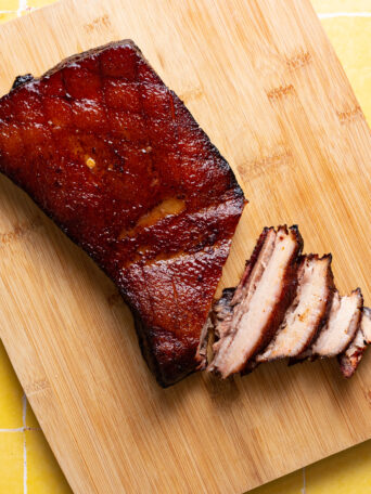 Sous vide pork belly sliced on wood cutting board.