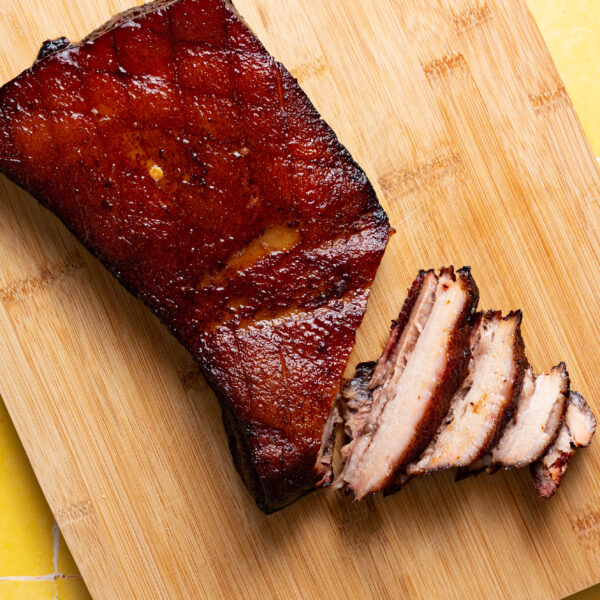 Sous vide pork belly sliced on wood cutting board.