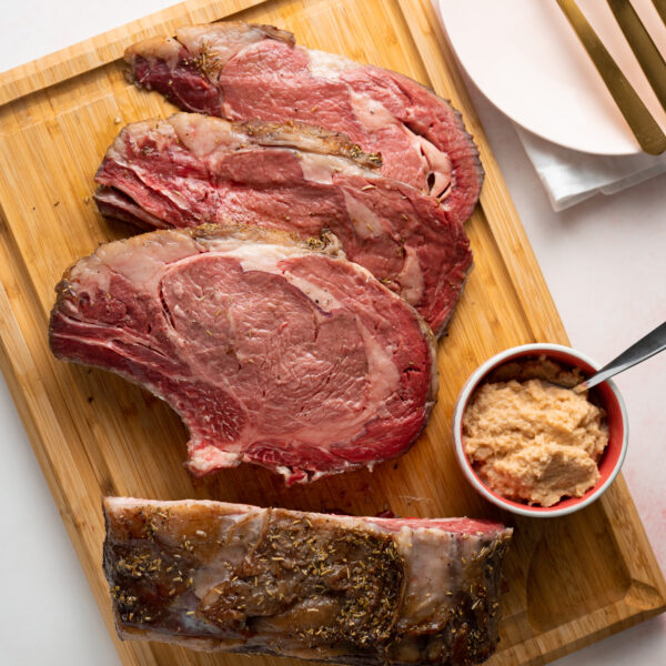 Sous vide prime rib on wood cutting board with bowl of horseradish.