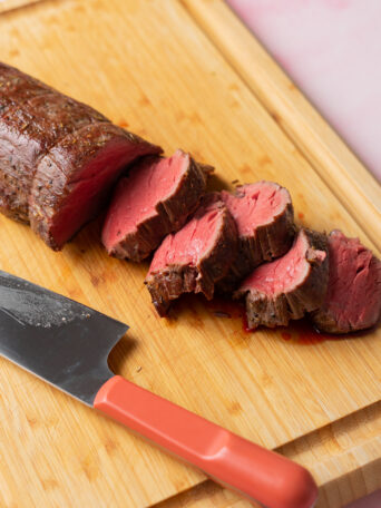 Sous vide beef tenderloin sliced on a wood cutting board