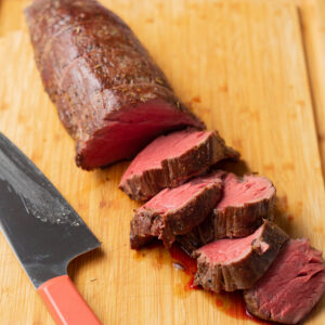 Sliced sous vide beef tenderloin on a wood cutting board