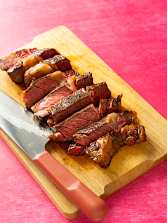 Sliced sous vide ribeye steak on wood cutting board.