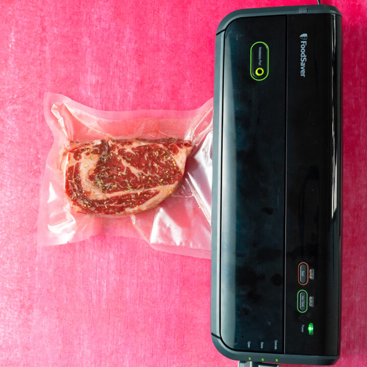 Vacuum sealer sealing a ribeye steak in a vacuum seal bag.