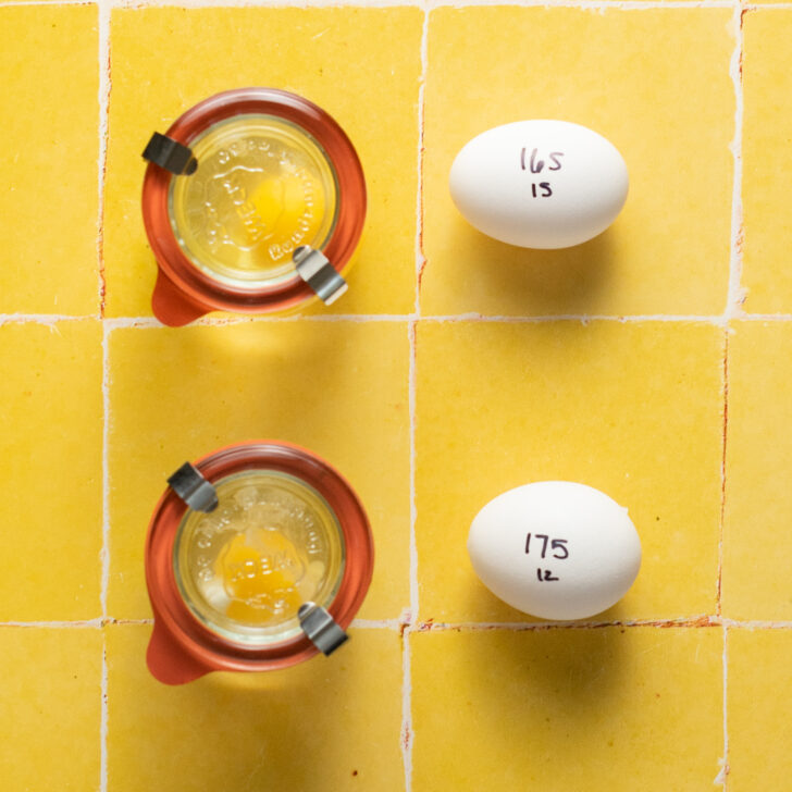 Two raw eggs in Weck jars with water and two whole raw eggs, each with their cooking times and temperatures written on them with sharpie.