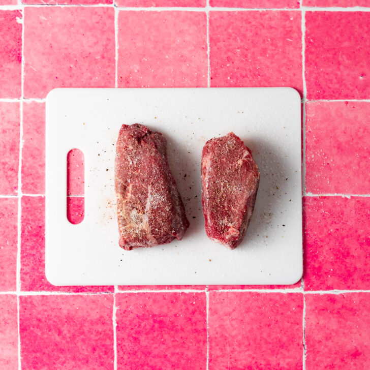 Sirloin steak seasoned with salt and pepper on cutting board