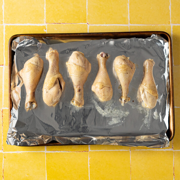 Sous vided chicken legs on a foil lined baking sheet.