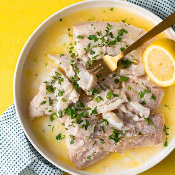 Sous vide cod in a lemon butter sauce on a white plate.