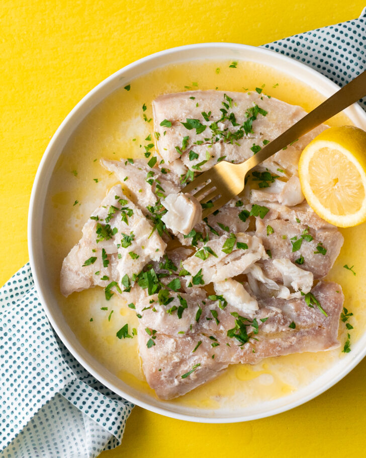 Sous vide cod in a lemon butter sauce on a white plate.