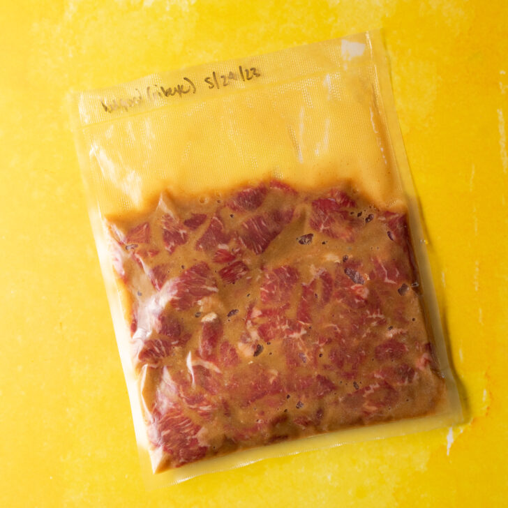 Vacuum seal bag of marinated bulgogi on yellow surface.